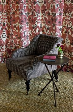 a chair sitting on top of a rug next to a table with a flower pot