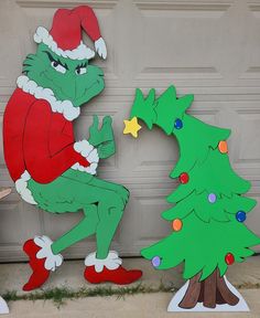 two cardboard cut outs of the grinch and christmas tree