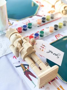 a close up of a wooden toy on a table with paintbrushes and paper