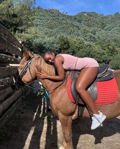 a woman is sitting on the back of a horse and hugging it's face