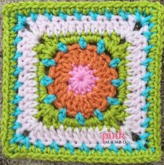 a crocheted square with an orange flower in the center and blue, pink, green, and white squares around it