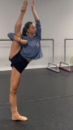 a woman is doing an acrobatic pose in the middle of a dance studio