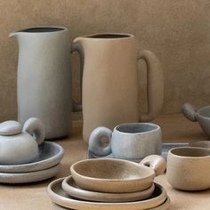 a table topped with lots of white and grey dishes next to cups and saucers