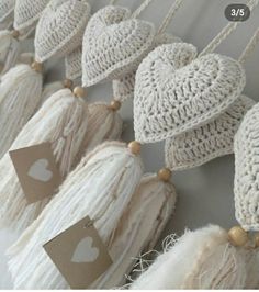 crocheted hearts hanging from the ceiling with tags attached to them and some tassels