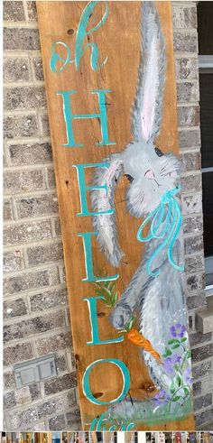 a wooden sign with a painting of a rabbit on it's side and the word hello