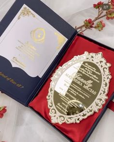 an open red and blue box with a wedding card in it on a white table cloth