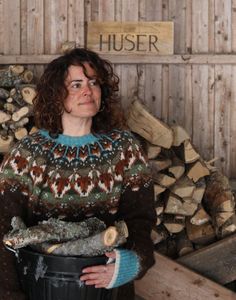 a woman standing next to a pile of wood