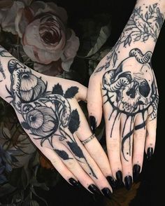 two hands with black and white tattoos holding each other's fingers in front of flowers