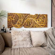 a couch with some pillows on it and a painting above the couch that is made out of wood