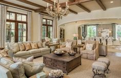 a living room filled with lots of furniture and a chandelier hanging from the ceiling