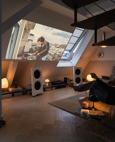 a man sitting on a couch in front of a projector screen that is hanging from the ceiling