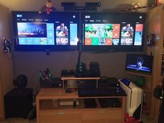 two large televisions mounted to the side of a wall next to a computer desk