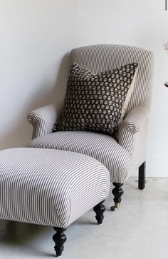 a striped chair and footstool in front of a white wall