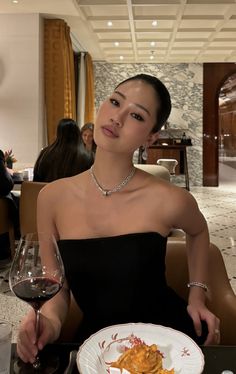 a woman sitting at a table with a plate of food and wine in front of her