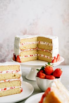 there is a cake with white frosting and strawberries on the plate next to it