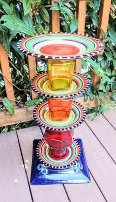 three colorful plates stacked on top of each other in the middle of a wooden deck