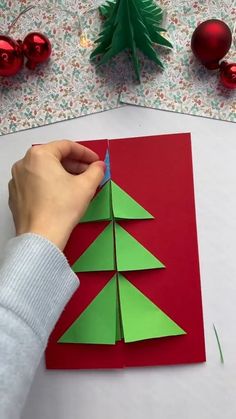 an ornament is placed on top of a folded paper with christmas decorations around it