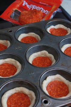 a muffin tin filled with cupcakes covered in red sauce next to a bag of pepperoni