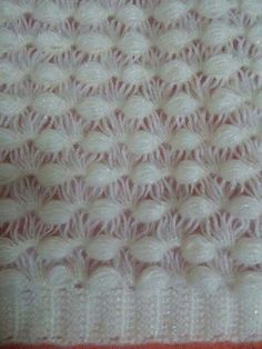 a white crocheted blanket is laying on top of a red and white table cloth