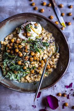 a bowl filled with pasta and garnished with chickpeas, parmesan cheese and herbs