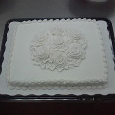 a square cake with white frosting roses on it