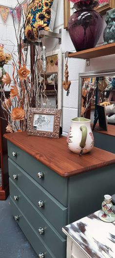 an old dresser is covered in vases and other items, including pictures on the wall