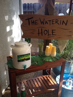 a wooden sign that says the waterin hole on top of a table next to a potted plant