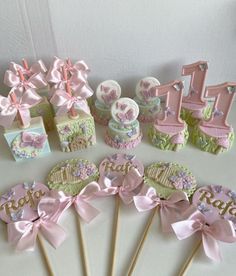 a table topped with lots of cupcakes covered in pink bows and decorations on top of cake sticks