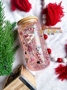 a pink mason jar sitting on top of a wooden block next to christmas decorations and ornaments