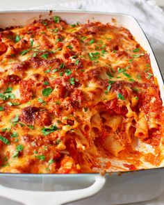 a casserole dish with meat, cheese and parsley on the top is ready to be eaten