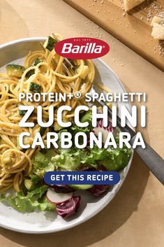 a white plate topped with pasta and veggies on top of a wooden table