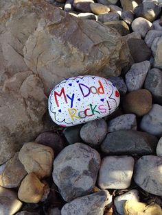 a rock with the words my dog rocks painted on it sits among some rocks and gravel