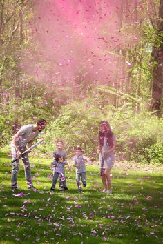 a group of people standing on top of a lush green field covered in pink confetti