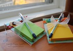 two small boxes with pens and markers on them sitting next to each other in front of a window