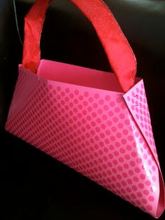 an origami bag sitting on top of a black table next to a cup