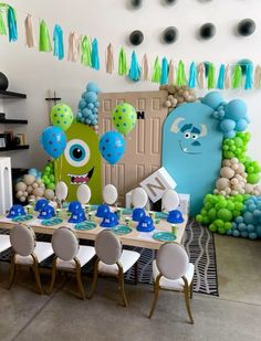 a table set up for a monster birthday party with balloons and decorations on the wall