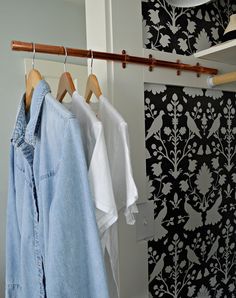 three shirts hanging on a clothes rail in front of a wallpapered room with black and white damask