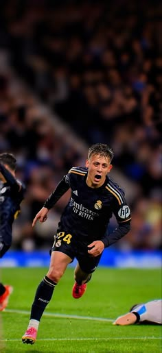 a soccer player is running with the ball in his hand while another player looks on