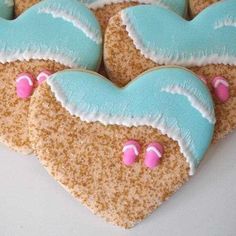 three heart shaped cookies decorated with blue and pink icing