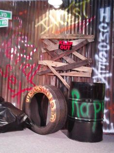 some old tires are sitting on the floor in front of a wall with grafitti