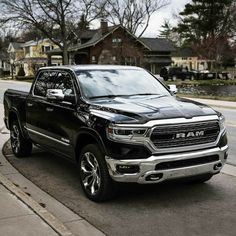 a black ram truck is parked on the side of the road in front of some houses