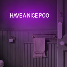 a purple neon sign above a toilet in a bathroom with the word have a nice poo on it