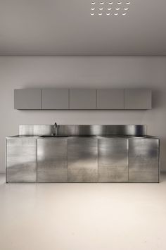 an empty kitchen with stainless steel cabinets and cupboards on the wall, in front of a white ceiling