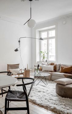 a living room filled with furniture and a white rug on top of a hard wood floor