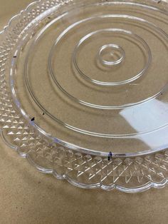 a clear glass platter sitting on top of a brown tablecloth covered countertop