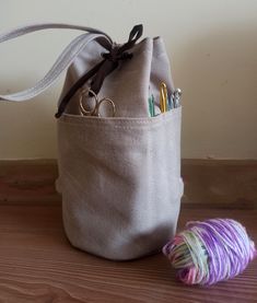 a bag that has some scissors in it and yarn next to it on the floor