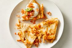 three pieces of quesadilla on a plate with sour cream and toppings