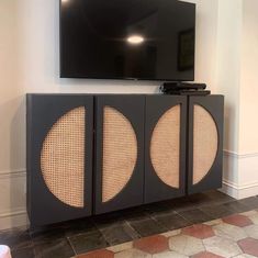 a flat screen tv mounted to the side of a wall next to a black cabinet