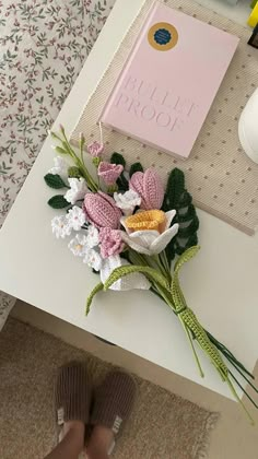 a bouquet of flowers sitting on top of a table next to a person's feet