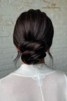 the back of a woman's head with dark brown hair in a low bun